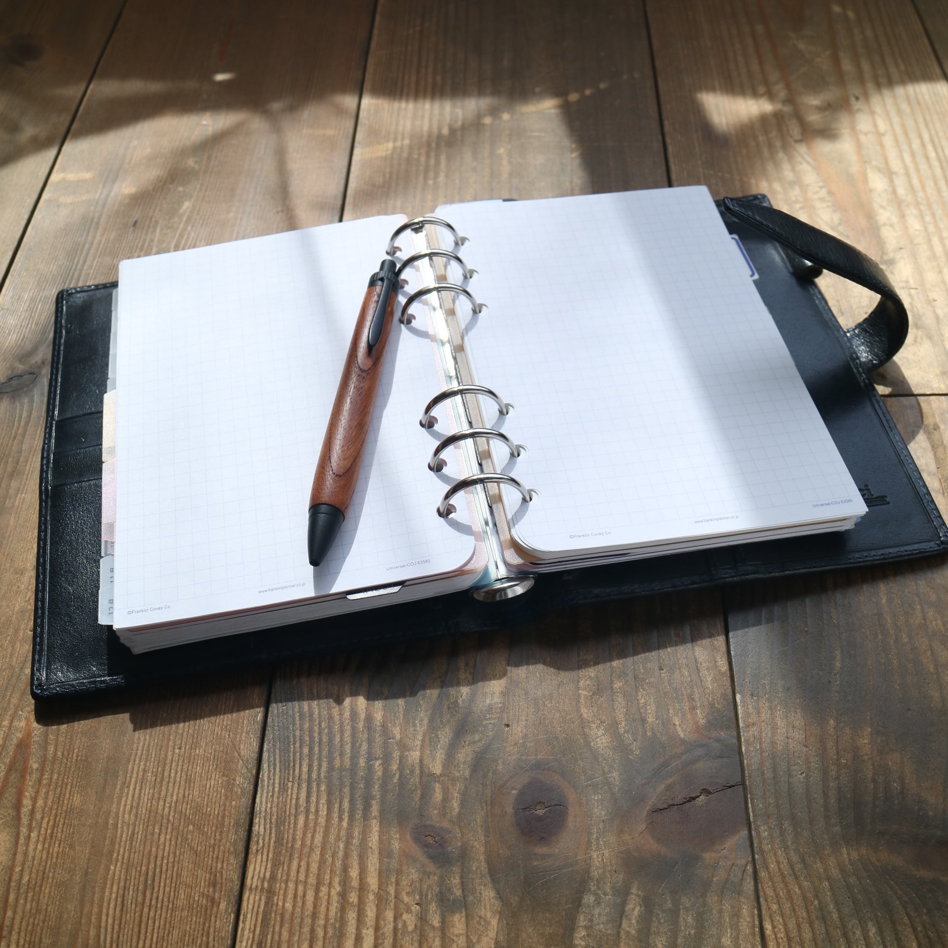 Handcrafted wooden pen resting on a leather system planner notebook